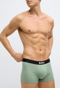 Bokserki w jasnym zielonym kolorze o dopasowanym kroju, z czarnym pasem oznaczonym napisem „BOSS”. Gładka tekstura, krótka długość i dopasowany fason.