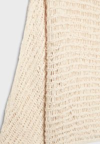 Béžová pletená tkanina so dvoma rôznymi vzormi otvoreného pletenia s textúrovanými vertikálnymi a diagonálnymi radmi.