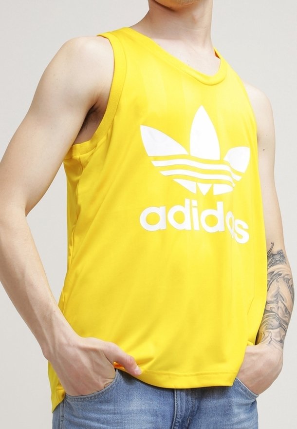 Maillot de sport sans manches jaune avec logo blanc Adidas et trois bandes; fabriqué en tissu synthétique lisse, doté d'une coupe décontractée et d'un col arrondi.