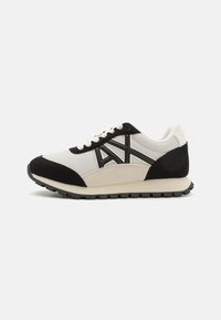 Men's sneakers with a white mesh upper, black suede accents, and a rubber sole. Features contrasting logo and lace-up design.