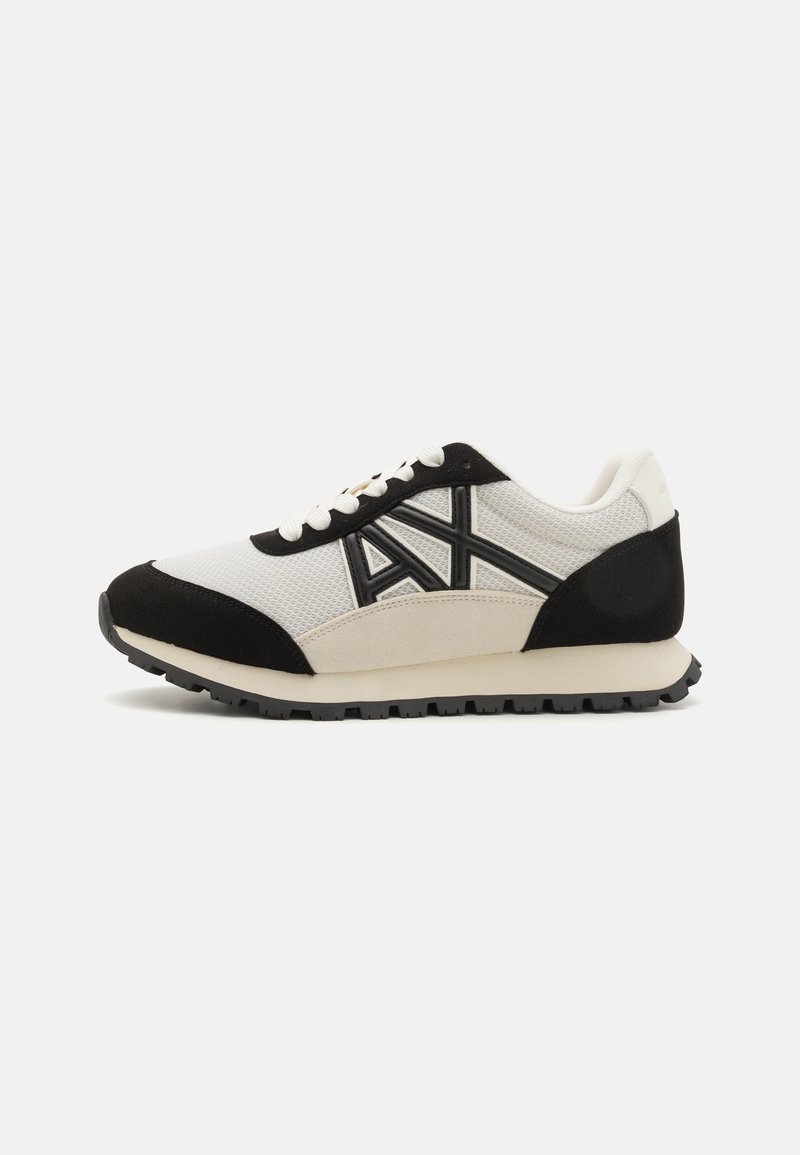 Men's sneakers with a white mesh upper, black suede accents, and a rubber sole. Features contrasting logo and lace-up design.