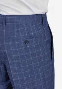 Donkerblauwe geruite broek met een gestructureerde stof, achterzak met een zwarte knop en zijzakken, ontworpen voor een getailleerde pasvorm.