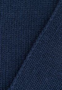 Marineblauwe gebreide stof met een ribbelstructuur. Het patroon bevat verticale lijnen en heeft een gladde, iets vlezige uitstraling.