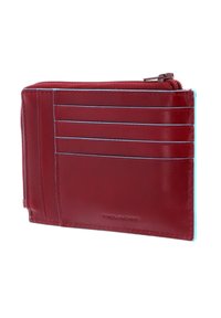 Portafoglio rosso in pelle con accenti blu, caratterizzato da più scomparti per carte e un vano con zip. Texture liscia, design moderno, forma compatta.