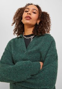 Maglione verde a maglia con scollatura a V profonda, maniche lunghe e una finitura texturizzata. Presenta un colletto e polsini a costine per un tocco di dettaglio in più.