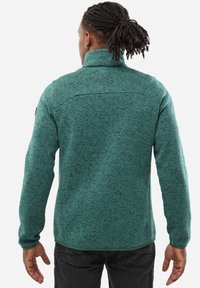 Aquamarine fleece jacket with a high collar, textured pattern, and long sleeves, featuring a subtle logo on the left shoulder.