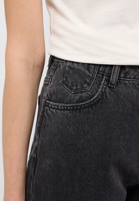 Černé džíny z denimu s jemně texturovaným povrchem, pět kapsového designu a standardním zap�ínáním na knoflík a zip. Akcentované švy a stehy.