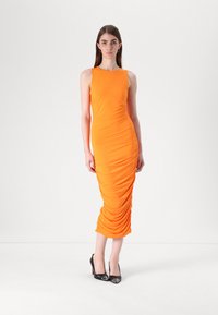 Robe bodycon orange en tissu extensible, dotée de détails froncés sur les côtés, avec un design sans manches élégant et une longueur midi.