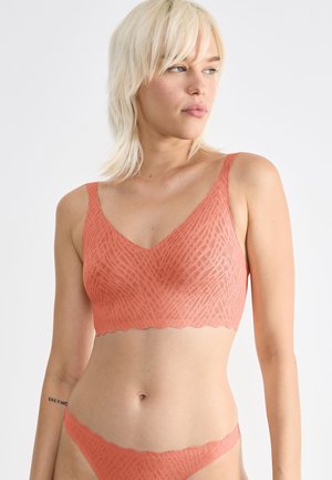 Bralette de couleur pêche avec un motif géométrique texturé, des bords festonnés et un bas de bikini assorti, fabriqué à partir d'un matériau doux.