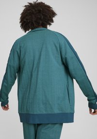 Teal mønstrede jakke med herringbone tekstur; har en afslappet pasform, lange ærmer og sideslidser for komfort.