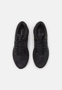 Ett par svarta Nike löparskor med meshöverdelar och snören, sett ovanifrån på en vit bakgrund.