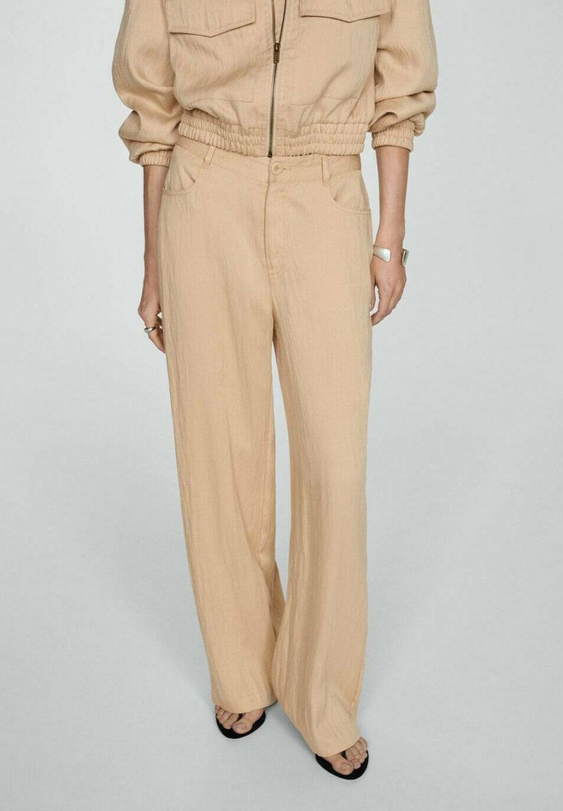 Beige wijde broek van een textuurstof, met voorzakken en een knoopsluiting, gestyled met een bijpassende blazer voor een gecoördineerde look.