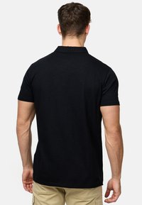Sort kortærmet polo skjorte med krave, lavet af blødt stof. Har en lige pasform med en ren afslutning ved kanten og ærmerne.