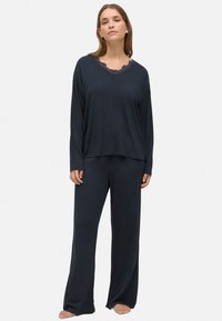 Conjunto de loungewear en azul marino que incluye una parte superior de manga larga con un escote de encaje con forma de ondas y pantalones sueltos a juego, confeccionados en un tejido suave.