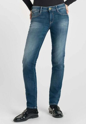 Jean en denim bleu à coupe slim, avec fermeture à bouton, cinq poches, et un léger délavage sur les cuisses. Texture lisse et design classique.