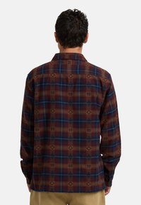 Bruine en blauwe geruite shirt met een button-down kraag, lange mouwen en een geometrisch patroon throughout. Zachte textuur en regular fit.