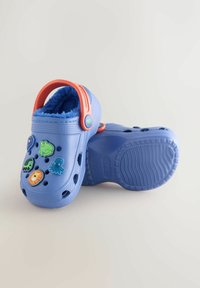 Blue clogs with a fuzzy interior, featuring colorful animal-themed decorations and drainage holes. Orange heel strap for secure fit.