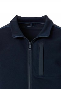 Mørkeblå zip-up jakke med tekstureret stof, højt krave og kontrasterende trim. Har en frontlomme og glat lynlås.