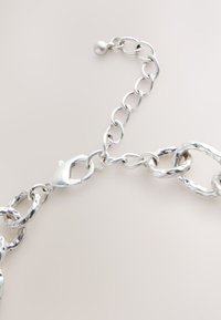 Silver chain bracelet with irregular oval links and a lobster clasp, featuring an adjustable chain with a small round end bead.