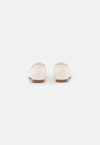 Světle růžové kožené boty s nízkým podpatkem a zaoblenou špičkou. Mají hladkou texturu a minimalistický design, s jemným detailem na zadní straně.