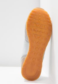 Sneaker sole with a textured orange rubber bottom, featuring a patterned grip and gray upper materials with subtle details along the sides.
