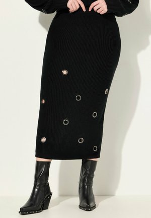 Zwarte geribbelde gebreide rok met ronde metalen accenten. Gestyled met strakke zwarte platformlaarzen, met een spitse neus en studdetails.