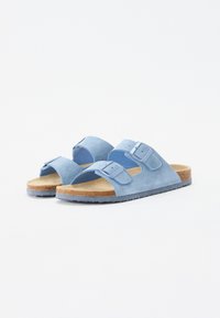 Ljusblå mocka slide-sandaler med två justerbara remmar. Korkfotbädd, gummisula med texturerat mönster och öppen tå-design.