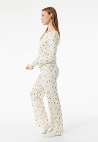 Lättviktig, krämfärgad pyjamasuppsättning med ribbad textur och små saxmönster, med en avslappnad passform och långa ärmar.