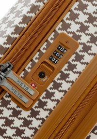 Braun-weiße Hahnentritt-Mustergepäckstücke mit strukturierter Oberfläche, ausgestattet mit zwei Reißverschlüssen und einem Kombinationsschloss auf einem beigefarbenen Akzentpanel.