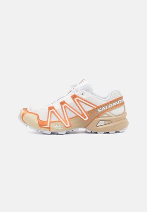 Weißer und beiger Salomon Trailrunning-Schuh mit orangefarbenen Akzenten, Mesh-Obermaterial und sichtbarer M&S Contagrip-Sohle.