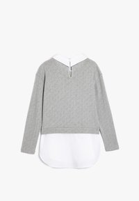 Suéter gris con un patrón de diamantes texturizado, cuello blanco y diseño de espalda abierta. Superpuesto a un dobladillo tipo camisa blanca. Manga larga.
