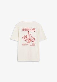 Camiseta de manga corta color crema con estampado gráfico rojo de dados y cerezas, con texto y detalles del evento en la parte posterior. Material de algodón.