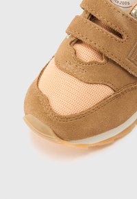 Καφέ και ροδακινί αθλητικό παπούτσι με μαλακό ανώτερο μέρος από σουέντ, πάνελ από δίχτυ, λουριά με βέλκρο και υφή λαστιχένιας σόλας.