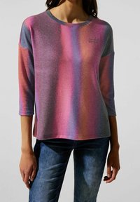 Tričko s dlouhými rukávy a kulatým výstřihem, s gradientem růžové, fialové a šedé barvy. Měkká textura, s logem na hrudi.