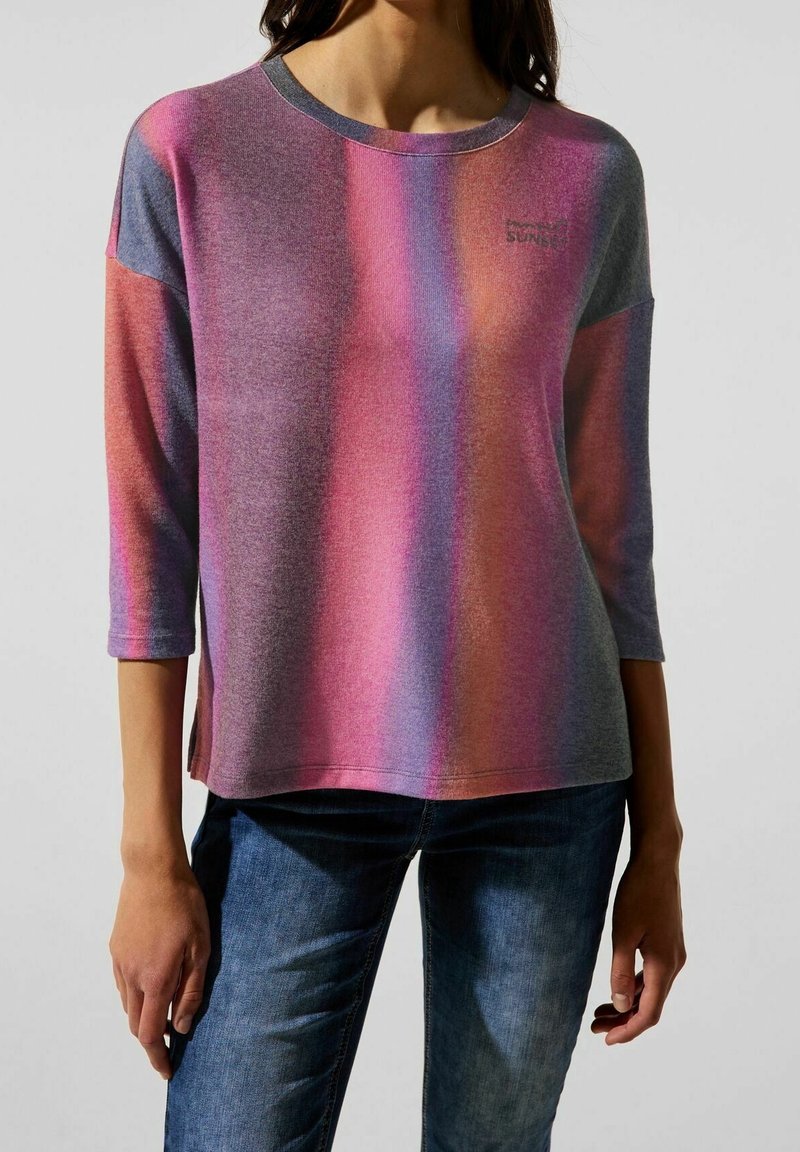 Tričko s dlouhými rukávy a kulatým výstřihem, s gradientem růžové, fialové a šedé barvy. Měkká textura, s logem na hrudi.