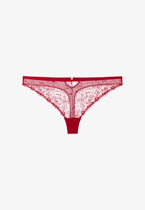 Červené krajkové tanga s květinovou výšivkou, vroubkovanými okraji a malým přívěskem ve tvaru srdce uprostřed pasu.