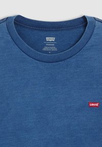 Modrá bavlněná tričko s kulatým výstřihem, krátkými rukávy a malou červenou nášivkou loga Levi's na levé hrudi.
