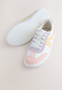 Baskets blanches avec des accents en daim rose pastel, violet et jaune, lacets blancs, semelles blanches texturées et semelles intérieures imprimées léopard.