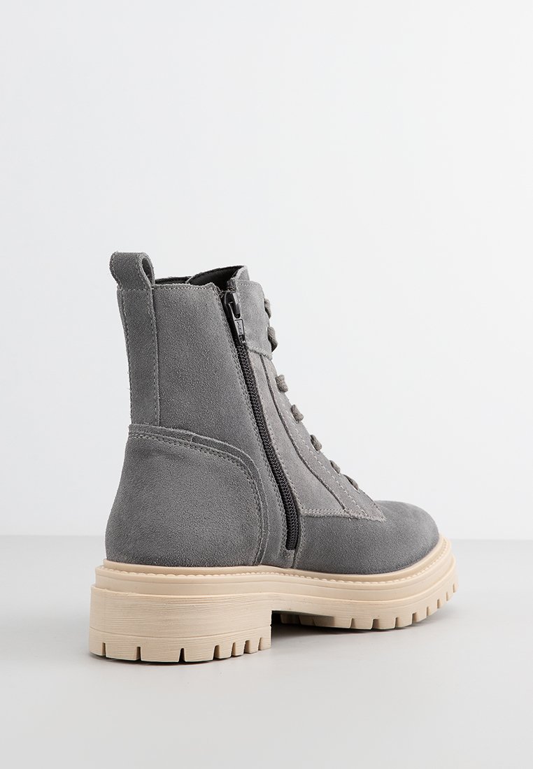 Graue Wildleder-Stiefeletten mit einem seitlichen Reißverschluss, Schnürdesign, klobiger beigefarbener Sohle und strukturierten Details im Obermaterial.