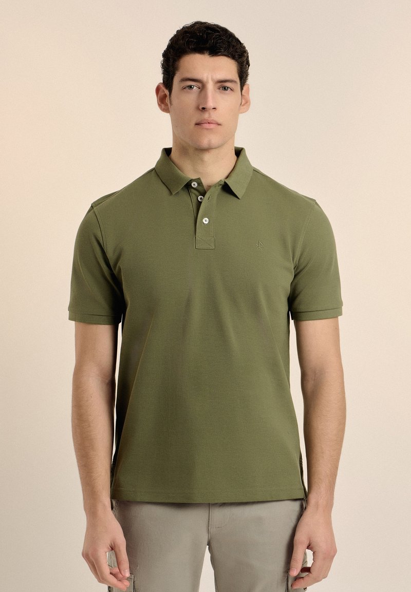 Polo de color verde oliva hecho de tela texturizada, con cuello, tapeta de tres botones y sutil bordado del logo en el pecho.