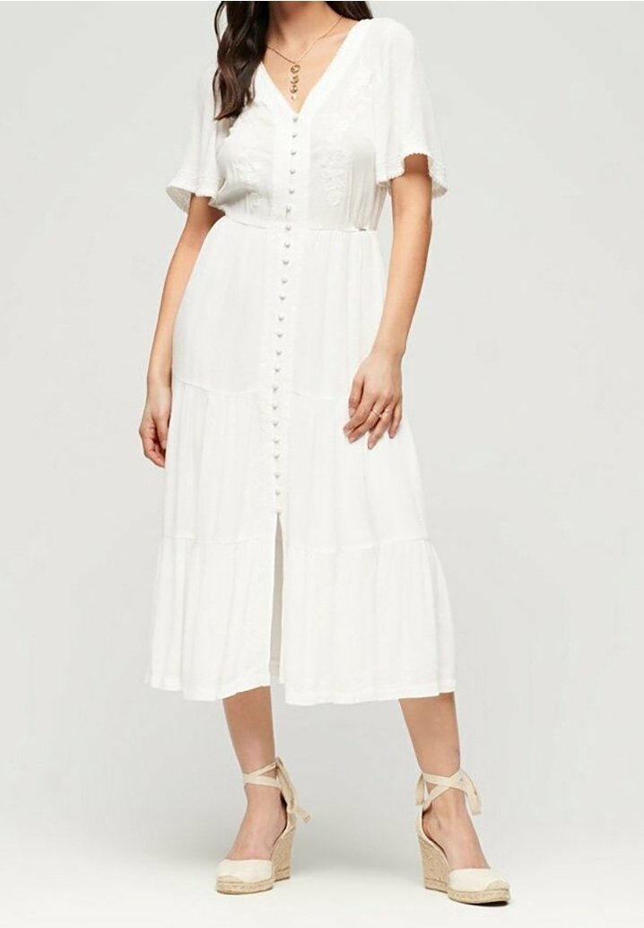 Biała midi sukienka z krótkimi bufkami, z przodu na guziki, w warstwowy wzór i lekką teksturę. W połączeniu z beżowymi espadrylami na obcasie.