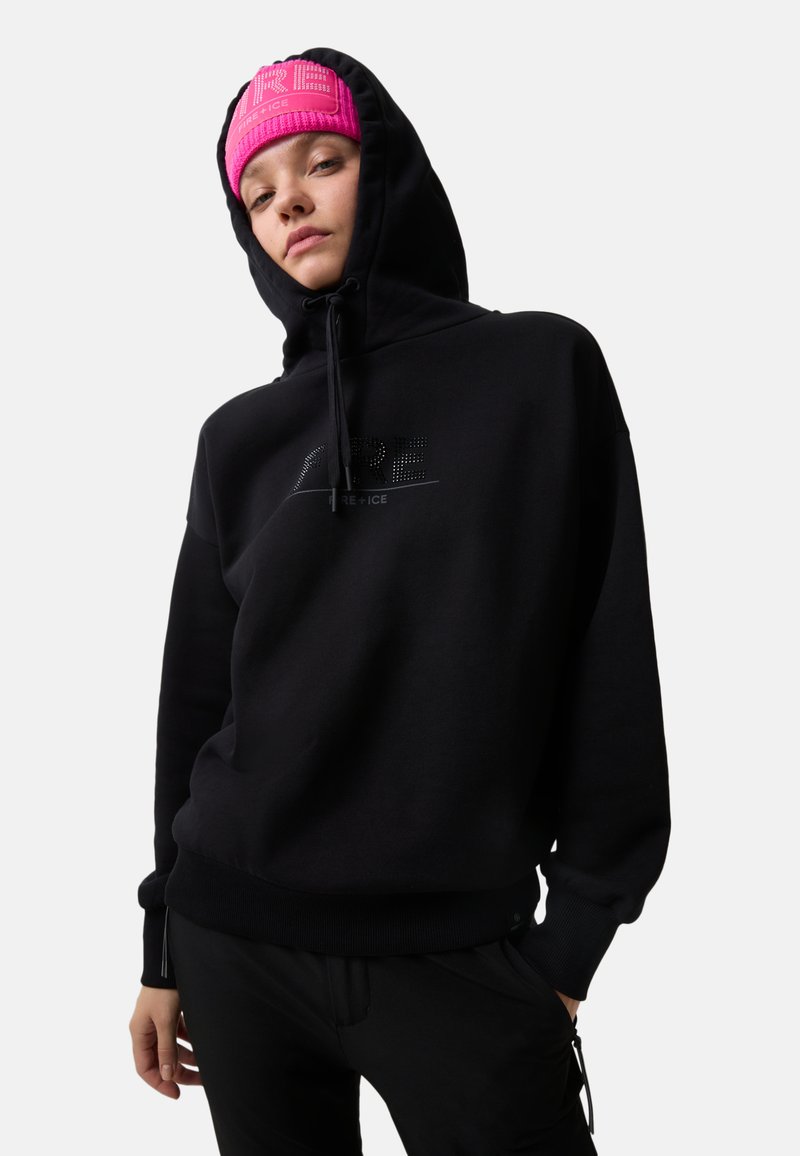 Person in einem schwarzen Hoodie mit dem Text "FIRE+ICE" und einer rosa gestrickten Mütze mit "FIRE+ICE" Branding auf einem hellgrauen Hintergrund.