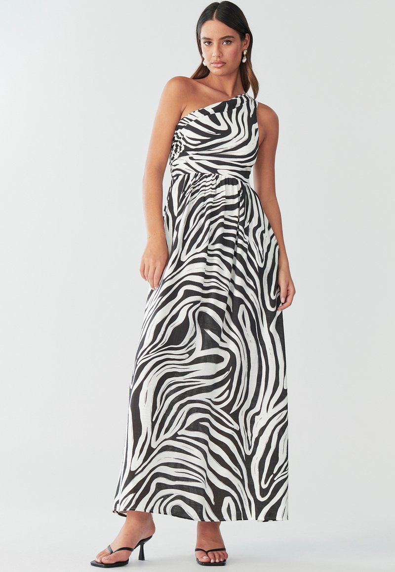 Sort-hvid zebra print maxi kjole med asymmetrisk halsudskæring, rynket detaljer i siden og flydende stof. Båret med sorte hæle med stropper.