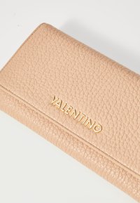 Lys rosa lær lommebok med strukturert overflate. Har en gull "VALENTINO"-logo på forsiden og en fold-over design.