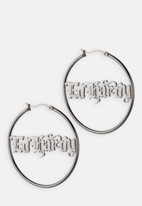 Pendientes de aro plateados con un diseño calado que presenta el texto "Ed Hardy" en una fuente decorativa. Textura suave y acabado pulido.