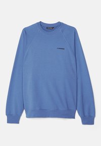 Blå sweatshirt med raglanärmar, rund halsringning och en svart logotyp på bröstet. Tyget verkar vara slätt och lätt texturerat.
