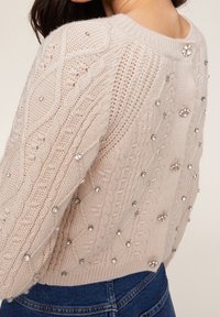 Hellrosaner gestrickter Pullover mit Kabelmustern, verziert mit silbernen Strasssteinen und einem Rundhalsausschnitt. Texturiert und in kürzerer Passform.