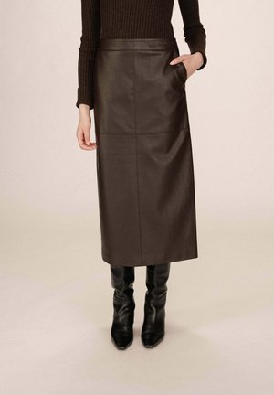 Falda midi de cuero marrón con una textura suave, con un diseño recto y bolsillos laterales, combinada con botas negras de tacón alto hasta la rodilla.