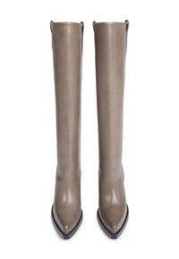 Une paire de bottes en cuir taupe arrivant au genou avec des orteils pointus et des bords de semelle noirs, se tenant debout sur un fond blanc.