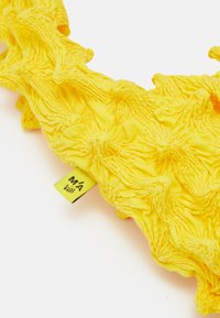 Yellow textured fabric accessory with gathered detailing, featuring a small label. The design is visually dynamic and vibrant.